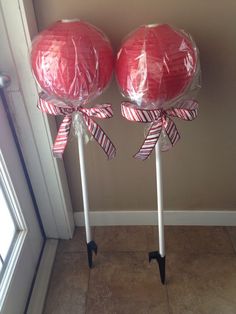 two red lollipops wrapped in cellophane on top of white poles