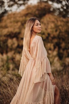 a woman standing in tall grass wearing a dress