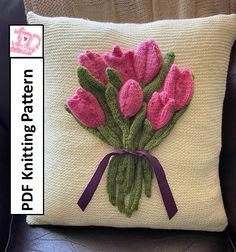 a knitted cushion with pink flowers on it