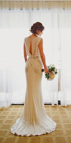 a woman in a wedding dress looking out the window