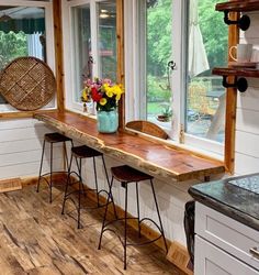 a kitchen with wood flooring and white painted walls, along with windows that look out onto the backyard