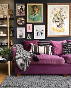 a living room with purple couches and pictures on the wall above it's coffee table