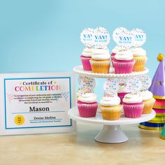 cupcakes are displayed on a cake stand next to a certificate for completion in the language of congratulations