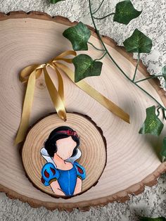 a wooden ornament with an image of snow white on it and a gold ribbon