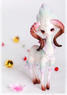 an animal with long horns standing in the snow next to some flowers and gold balls