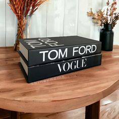 two black books sitting on top of a wooden table next to vases with flowers