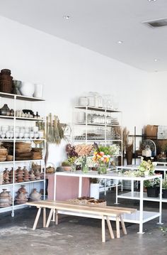 a room filled with lots of different types of vases and flowers on shelves next to each other