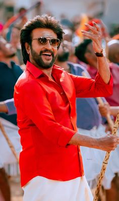 a man in red shirt and white pants holding a rope with both hands while standing next to other people