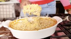 a person scooping food out of a casserole dish on top of an oven