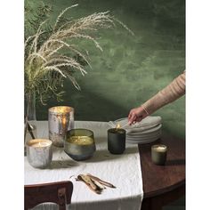 a woman is preparing food on a table with candles and other items in front of her