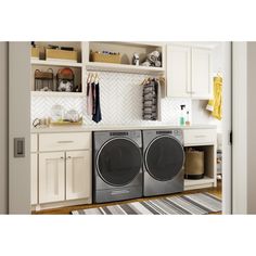 a washer and dryer in a room with white cupboards on the wall