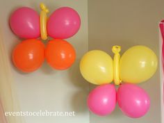 two balloons are attached to the wall and one is pink and yellow with orange on it