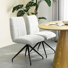 two chairs sitting next to each other on top of a wooden table in front of a potted plant