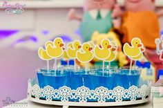 there are some little yellow ducks in the cupcakes on the cake stand with blue cups