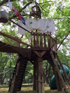 a wooden play structure in the middle of a park with lots of trees around it