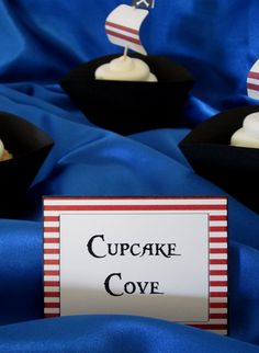 small cupcakes with white frosting and an american flag on top are sitting in black boxes