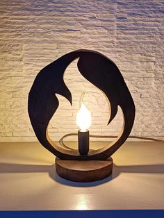 a lit candle sitting on top of a wooden table next to a white brick wall