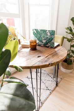 a wooden table with hairpin legs in front of a potted plant and window