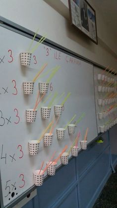 a white board with cups and numbers on it