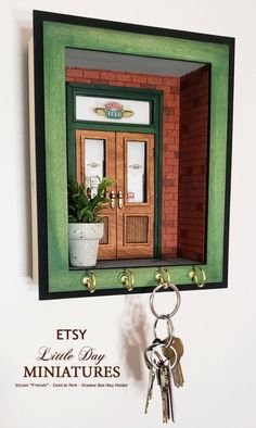 the key holder is made out of wood and has a green frame with an open door