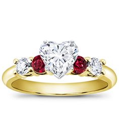 a heart shaped diamond ring with three stones on the band and two red diamonds in the middle