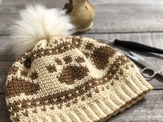 a knitted hat sitting on top of a wooden table next to a pair of scissors