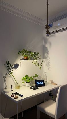 a white desk topped with a laptop computer next to a potted plant on top of it