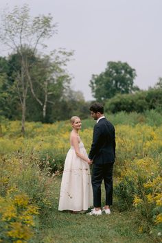 a bride and groom standing in the middle of a field