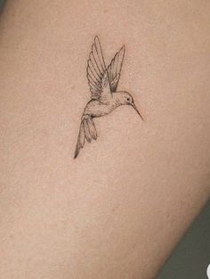 a small bird tattoo on the back of a woman's arm