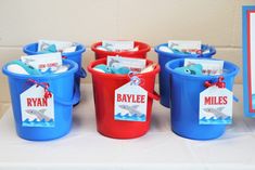 several buckets with name tags on them sitting on a table