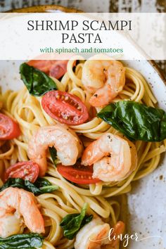 pasta with shrimp, spinach and tomatoes in a white bowl on a wooden table