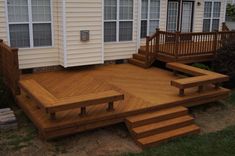 a wooden deck in front of a house with steps leading up to the back door