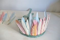 a birthday card with pink and blue feathers in a crown on a white tablecloth