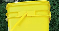 a yellow trash can sitting in front of some bushes and grass with the lid open