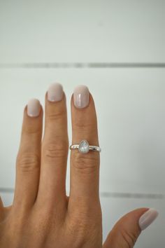 a woman's hand with a diamond ring on her left hand and a white background