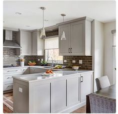 a kitchen with gray cabinets and white counter tops, along with a dining room table