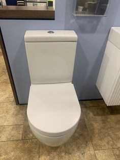 a white toilet sitting in a bathroom next to a radiator and towel dispenser