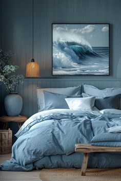 a bed with blue sheets and pillows in a room next to a painting on the wall