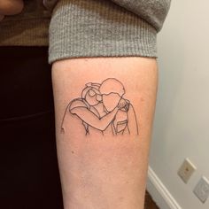 a woman's arm with a tattoo on it that has a drawing of two people hugging