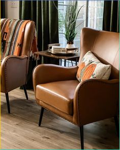 two brown leather chairs sitting next to each other on top of a hard wood floor