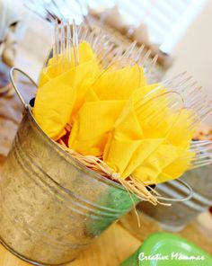 a metal bucket filled with yellow flowers sitting on top of a wooden table next to other items