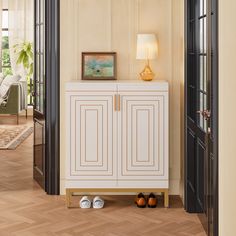 a white cabinet sitting on top of a hard wood floor next to a lamp and door