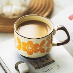 a cup of coffee sitting on top of a book next to marshmallows