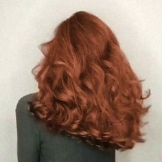 the back of a woman's head with long, curly red hair in it