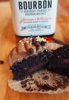 there is a chocolate cupcake and a bottle of bourbon on the table