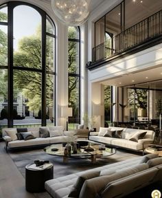 a large living room filled with lots of furniture next to tall windows and floor to ceiling windows