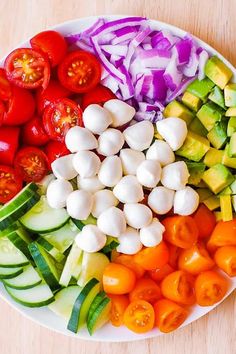 a white plate topped with lots of different types of vegetables on top of a wooden table