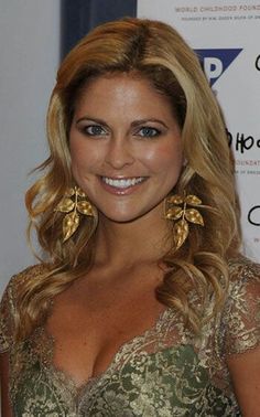 a woman in a gold dress smiling at the camera with big earrings on her ear