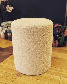 a white stool sitting on top of a wooden floor next to a potted plant