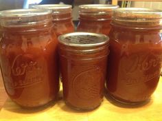 four jars filled with brown liquid sitting on top of a wooden table